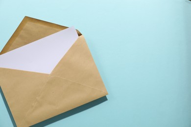 Photo of Kraft paper envelope with letter on light blue background, top view. Mockup for design