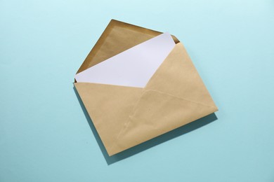 Photo of Kraft paper envelope with letter on light blue background, top view. Mockup for design