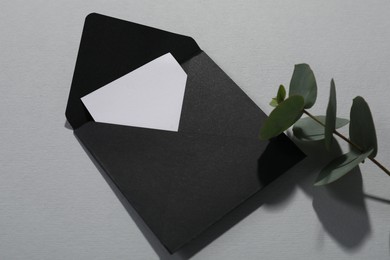 Photo of Paper envelope with letter and eucalyptus branch on grey background, closeup. Mockup for design