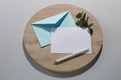 Photo of Paper envelope with letter, eucalyptus branch and pen on grey background, flat lay. Mockup for design