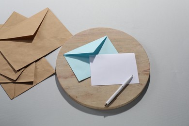 Photo of Paper envelopes with letter and pen on grey background, above view. Mockup for design