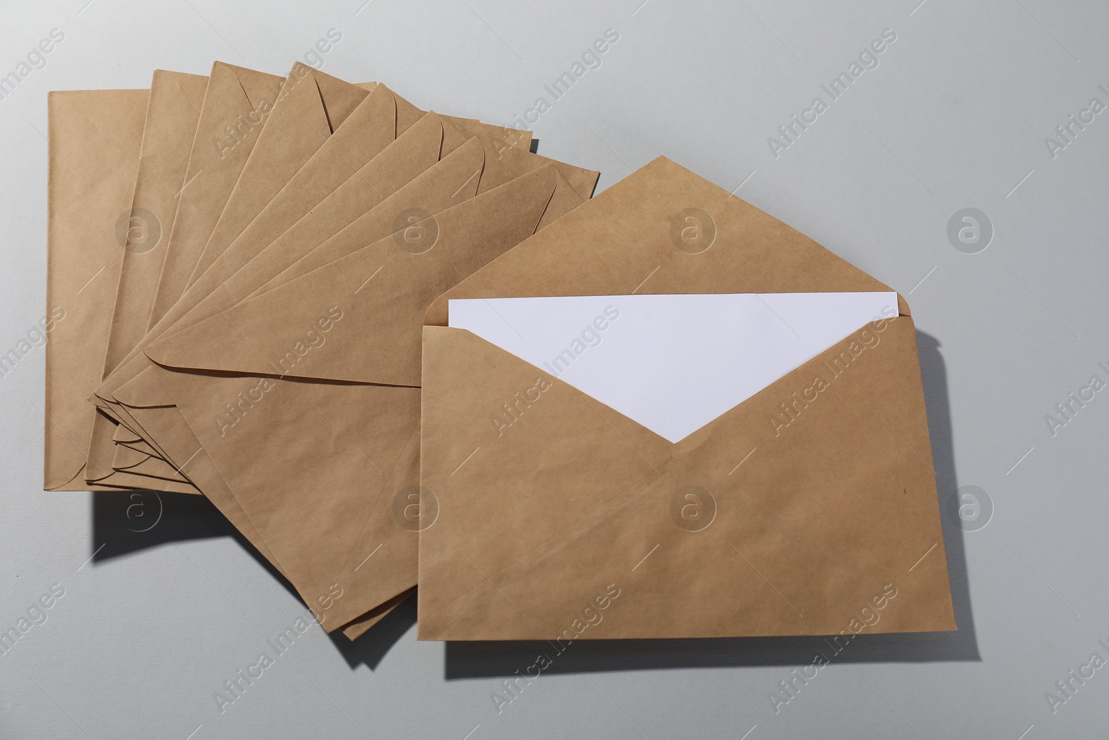 Photo of Kraft paper envelopes with letter on grey background, above view. Mockup for design