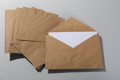 Kraft paper envelopes with letter on grey background, above view. Mockup for design