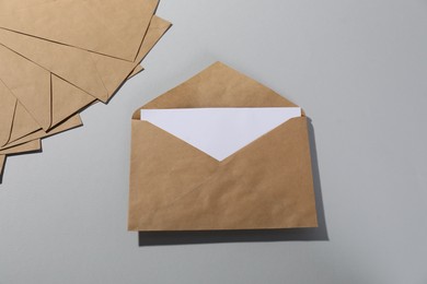 Photo of Kraft paper envelopes with letter on grey background, flat lay. Mockup for design