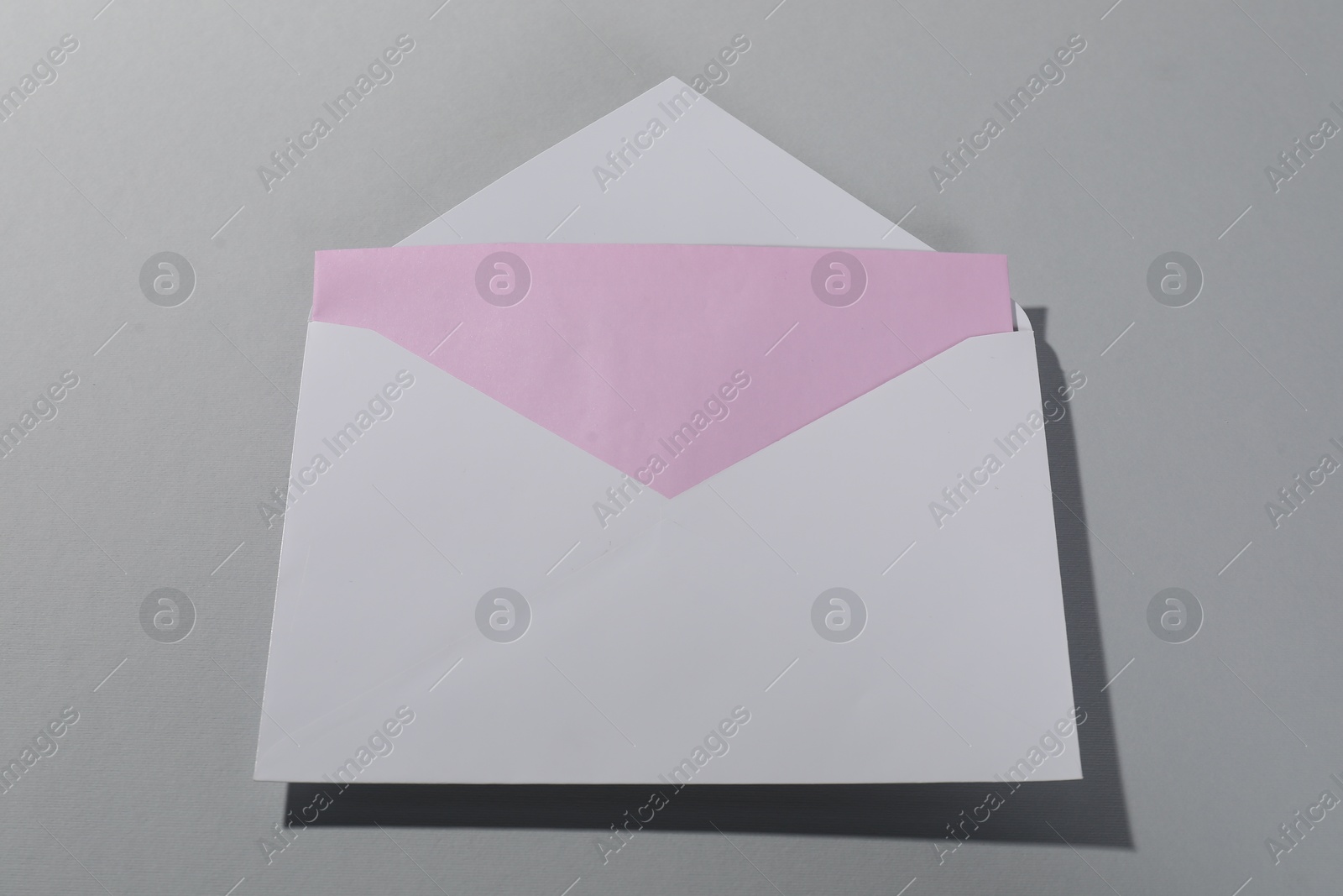 Photo of Paper envelope with letter on grey background, above view. Mockup for design