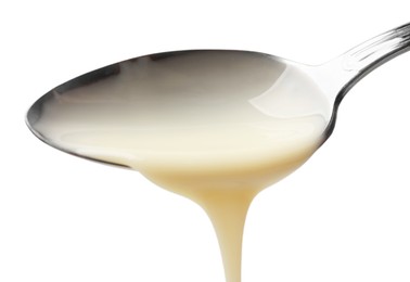 Photo of Delicious condensed milk pouring from spoon isolated on white