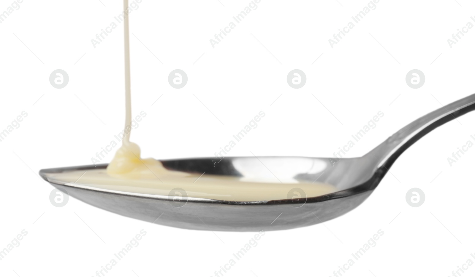 Photo of Delicious condensed milk pouring onto spoon isolated on white