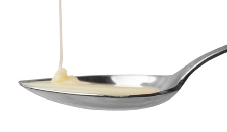 Photo of Delicious condensed milk pouring onto spoon isolated on white