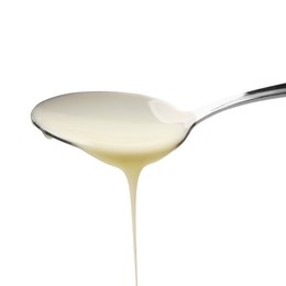 Photo of Delicious condensed milk pouring from spoon isolated on white