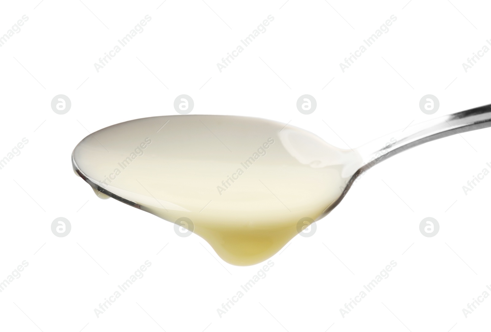 Photo of Delicious condensed milk pouring from spoon isolated on white