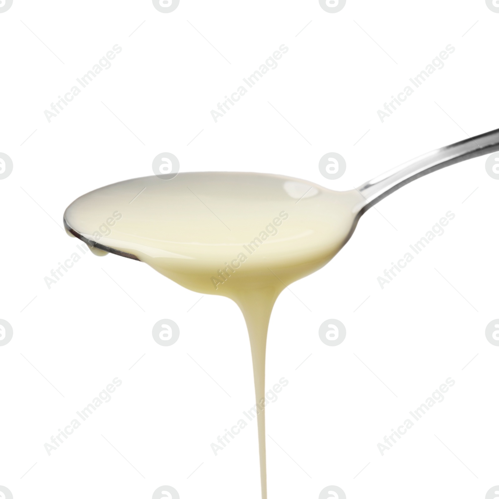 Photo of Delicious condensed milk pouring from spoon isolated on white