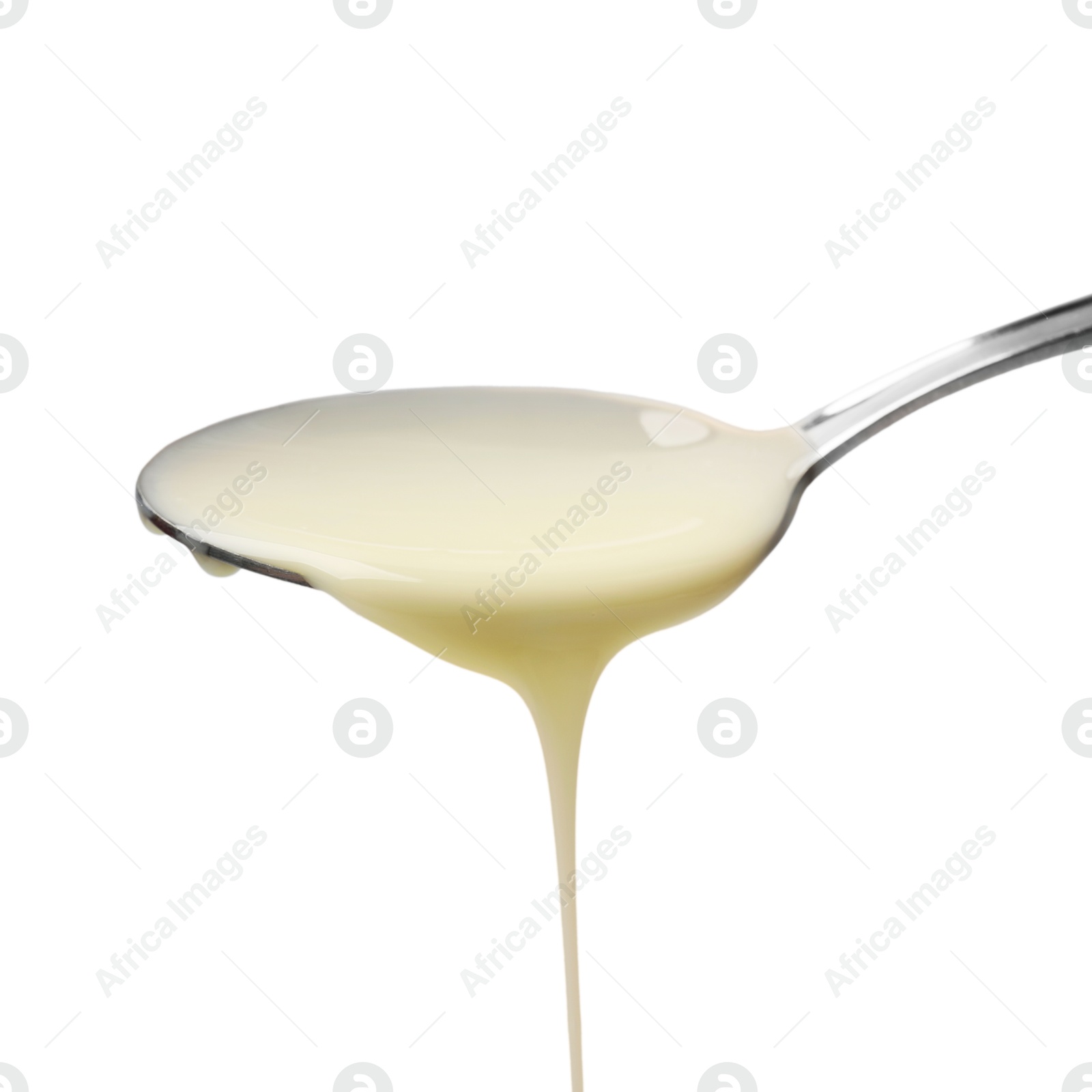 Photo of Delicious condensed milk pouring from spoon isolated on white