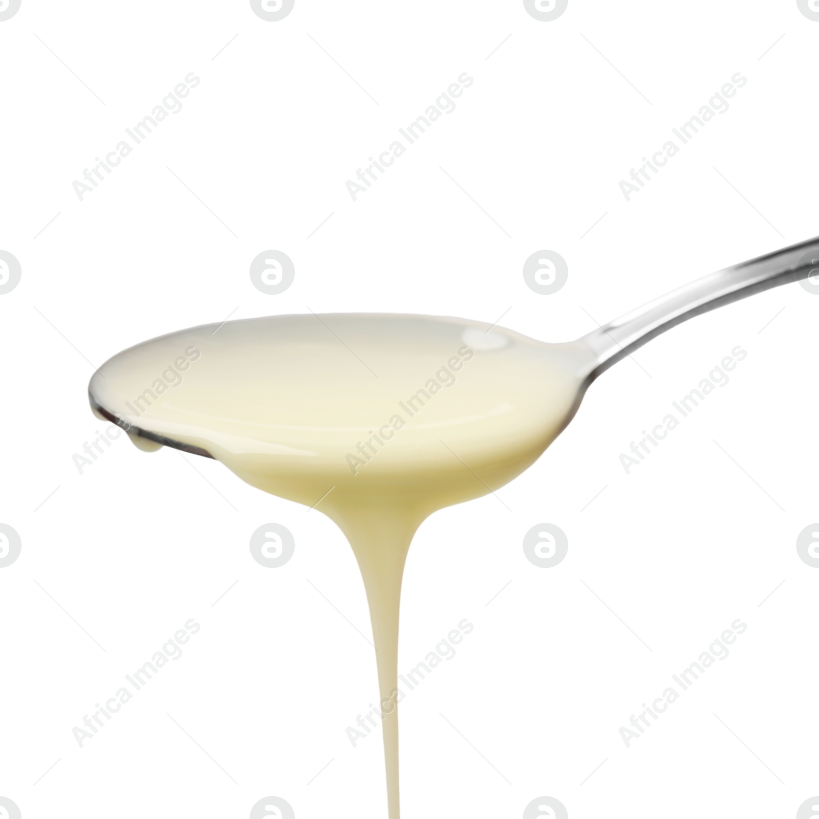 Photo of Delicious condensed milk pouring from spoon isolated on white