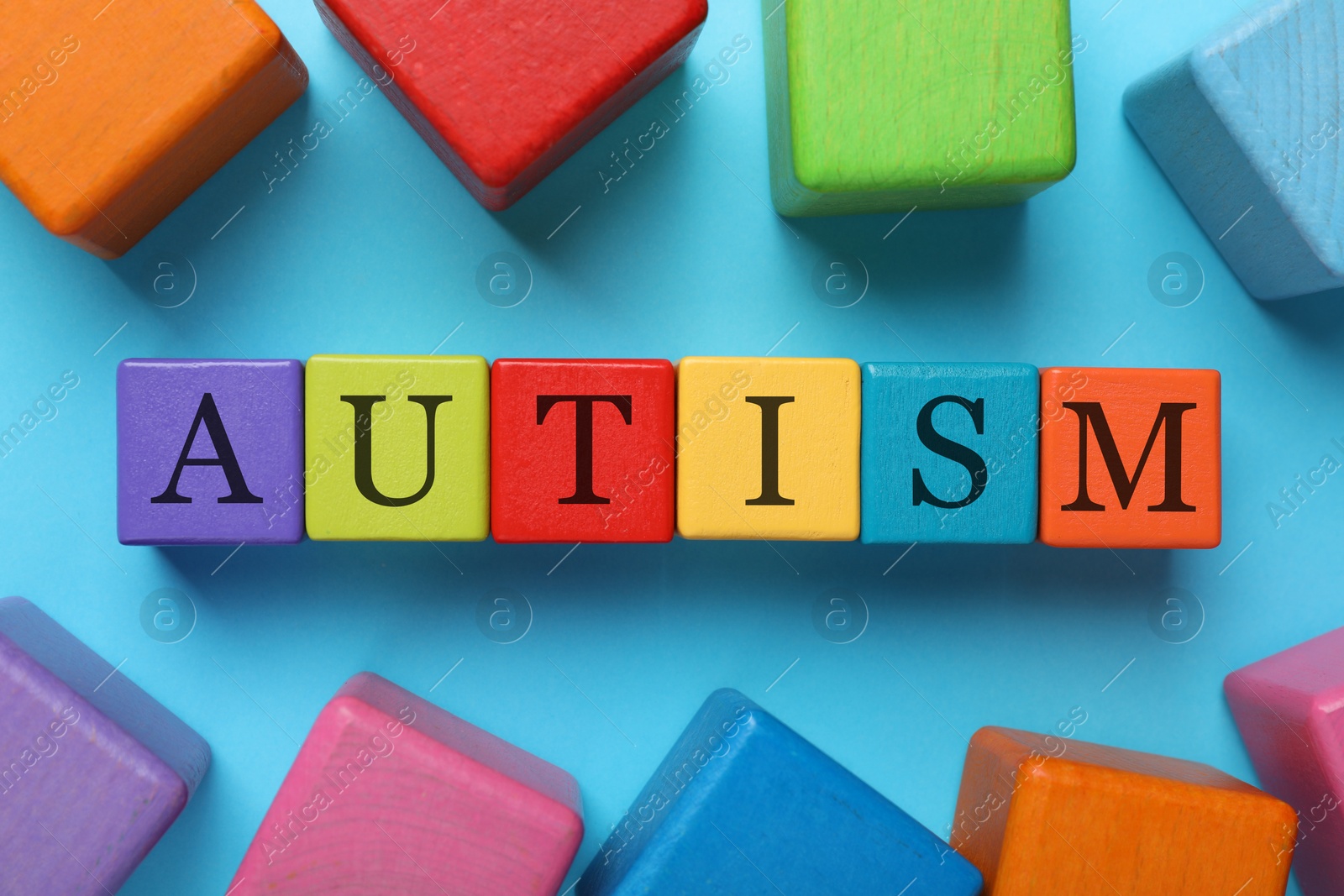 Photo of Word Autism made of colorful cubes on light blue background, top view