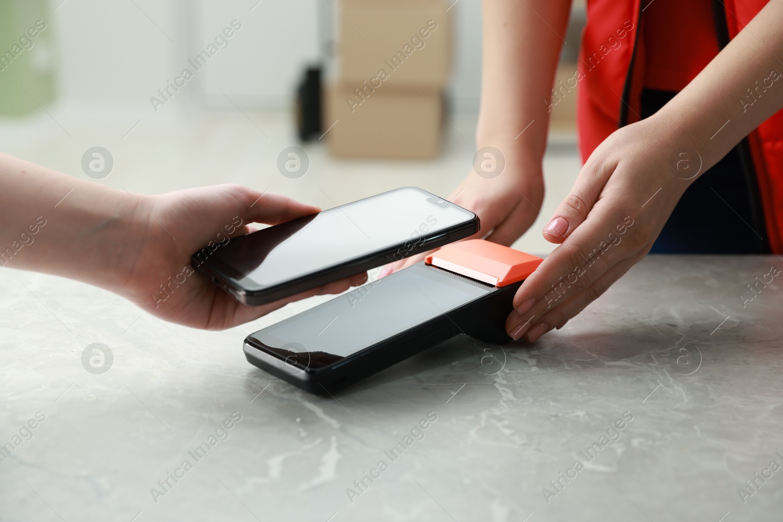 Photo of Woman paying for service with smartphone via terminal at table indoors, closeup