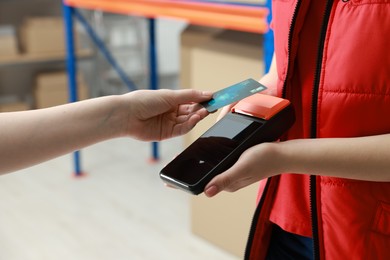 Photo of Woman paying for service with credit card via terminal indoors, closeup