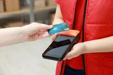 Photo of Woman paying for service with credit card via terminal indoors, closeup