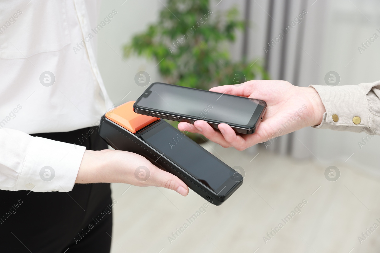 Photo of Woman paying for service with smartphone via terminal indoors, closeup