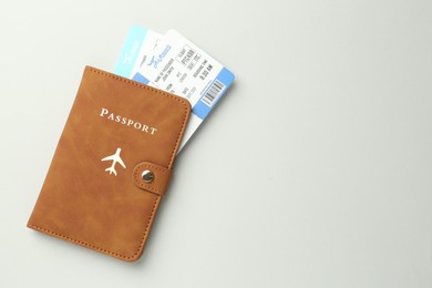 Photo of Passport in brown cover and flight tickets on light grey background, top view. Space for text