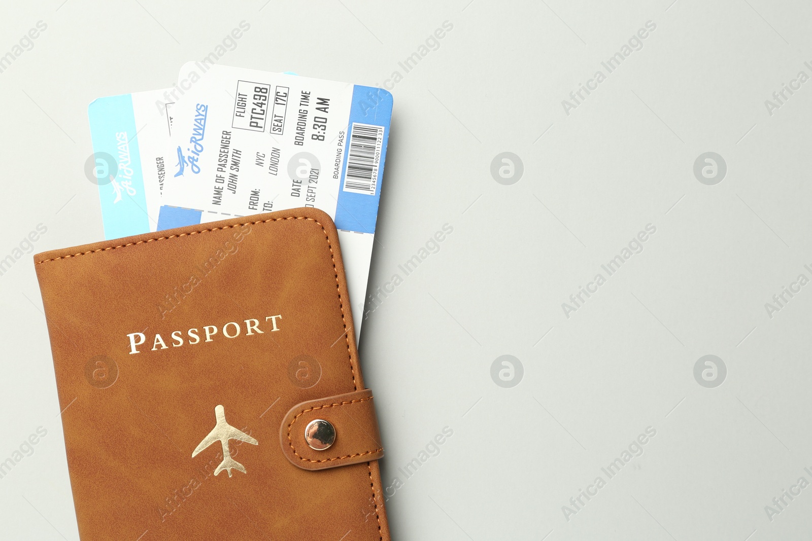 Photo of Passport in brown cover and flight tickets on light grey background, top view. Space for text