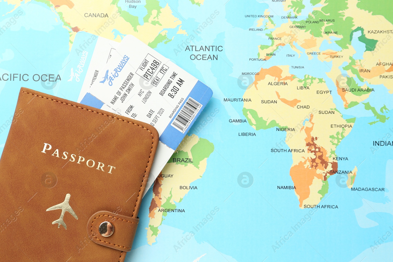 Photo of Passport in brown cover and flight tickets on world map, top view