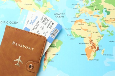 Photo of Passport in brown cover and flight tickets on world map, top view