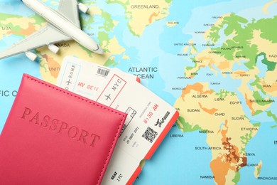 Photo of Passport in pink cover, flight tickets and plane model on world map, flat lay. Space for text