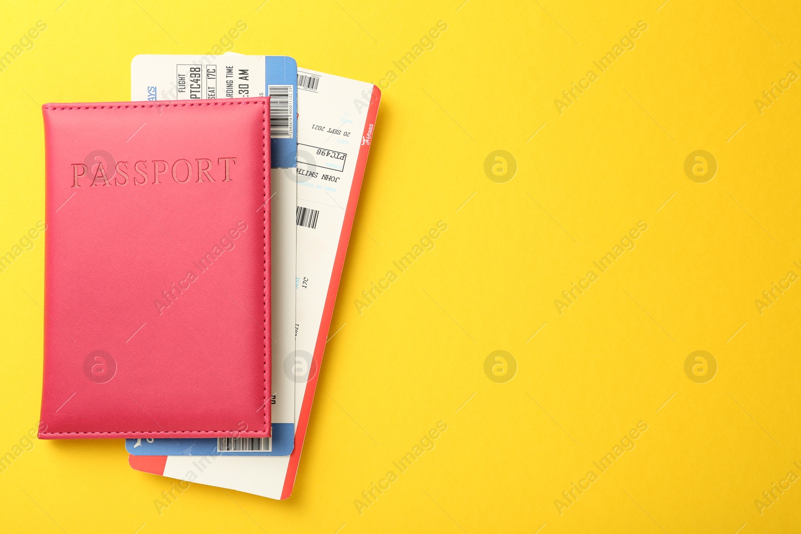 Photo of Passport in pink cover and flight tickets on yellow background, top view. Space for text