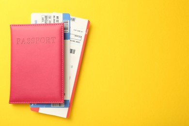 Photo of Passport in pink cover and flight tickets on yellow background, top view. Space for text