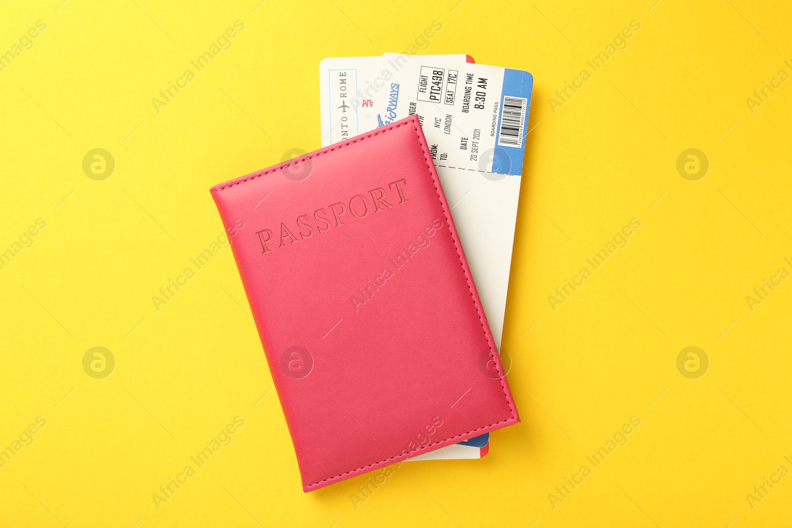 Photo of Passport in pink cover and flight tickets on yellow background, top view