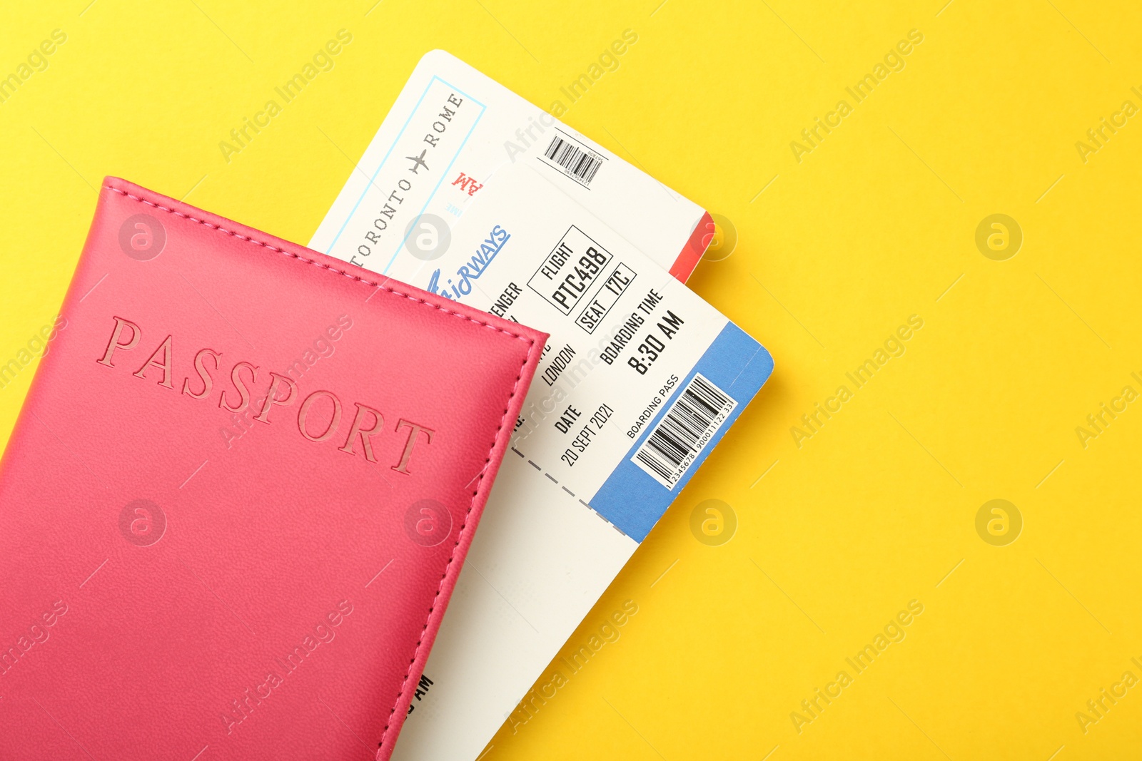 Photo of Passport in pink cover and flight tickets on yellow background, top view. Space for text