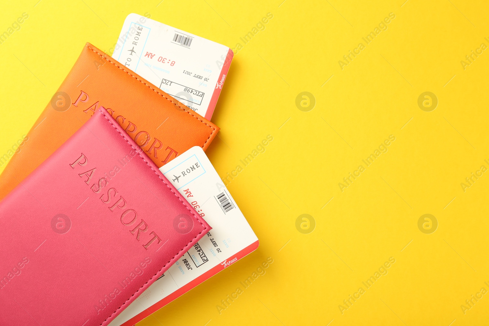 Photo of Passports in color covers and flight tickets on yellow background, top view. Space for text