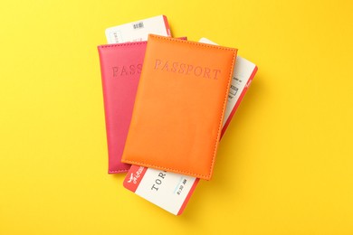 Photo of Passports in color covers and flight tickets on yellow background, top view