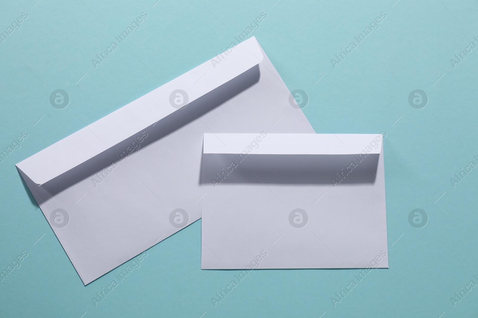 Photo of Paper envelopes on light blue background, top view. Mockup for design