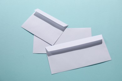 Photo of Paper envelopes on light blue background, flat lay. Mockup for design