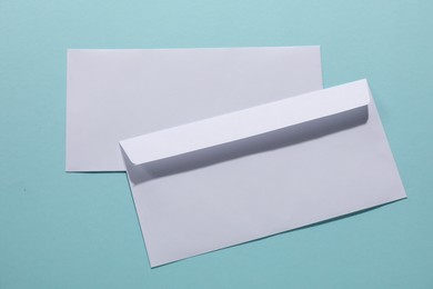 Paper envelopes on light blue background, top view. Mockup for design