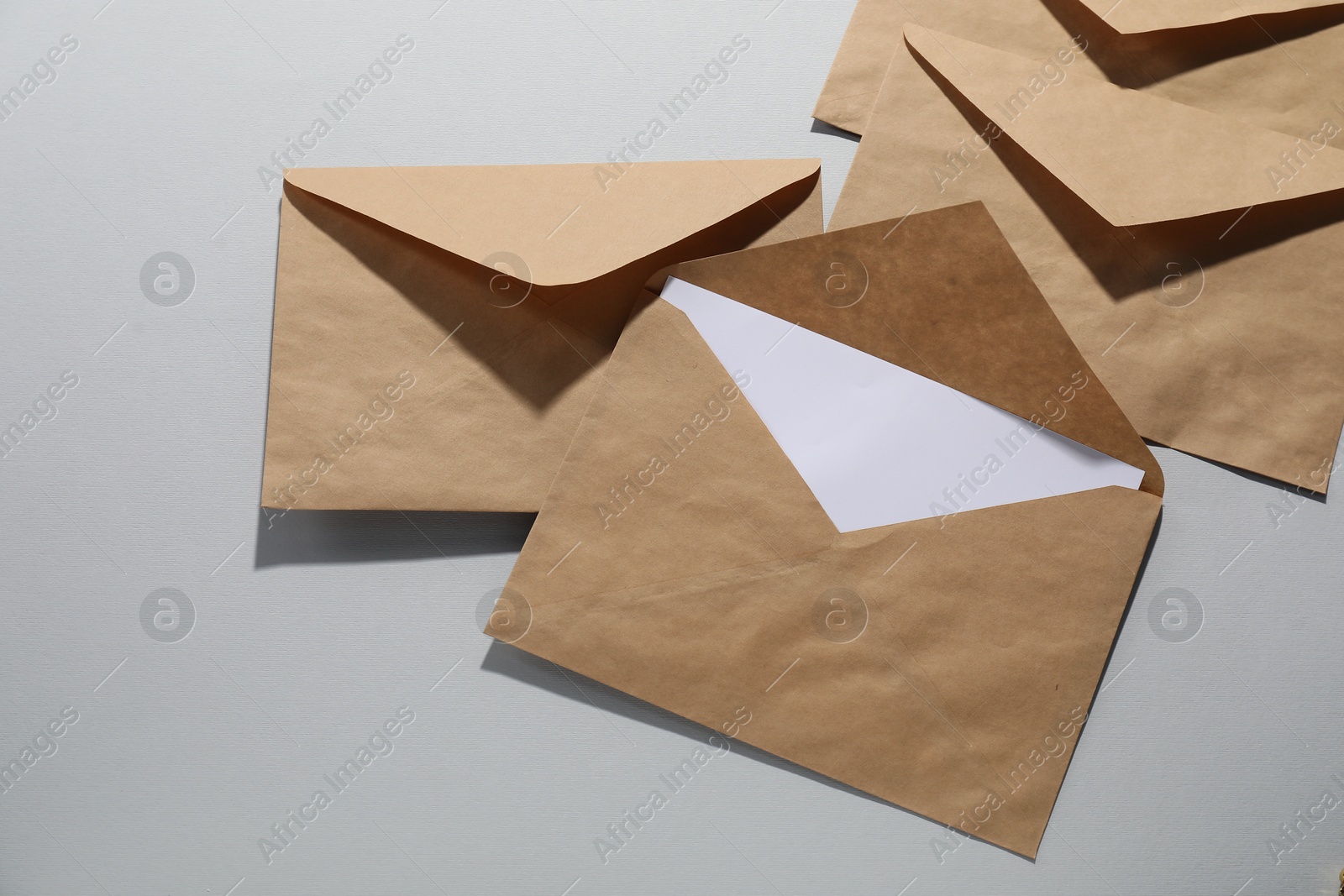 Photo of Kraft paper envelopes with letter on grey background, flat lay. Mockup for design