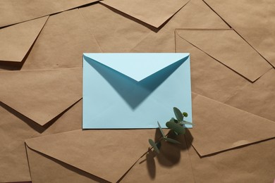 Photo of Paper envelopes and eucalyptus branch as background, top view. Mockup for design