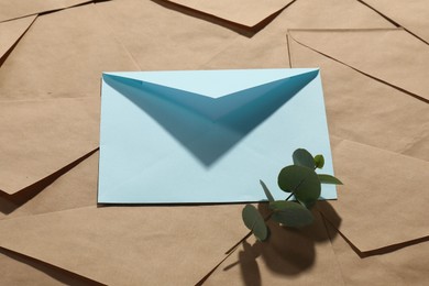 Photo of Paper envelopes and eucalyptus branch as background, above view. Mockup for design