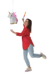 Photo of Happy woman hitting unicorn shaped pinata with stick on white background