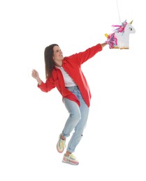 Photo of Happy woman hitting unicorn shaped pinata with stick on white background