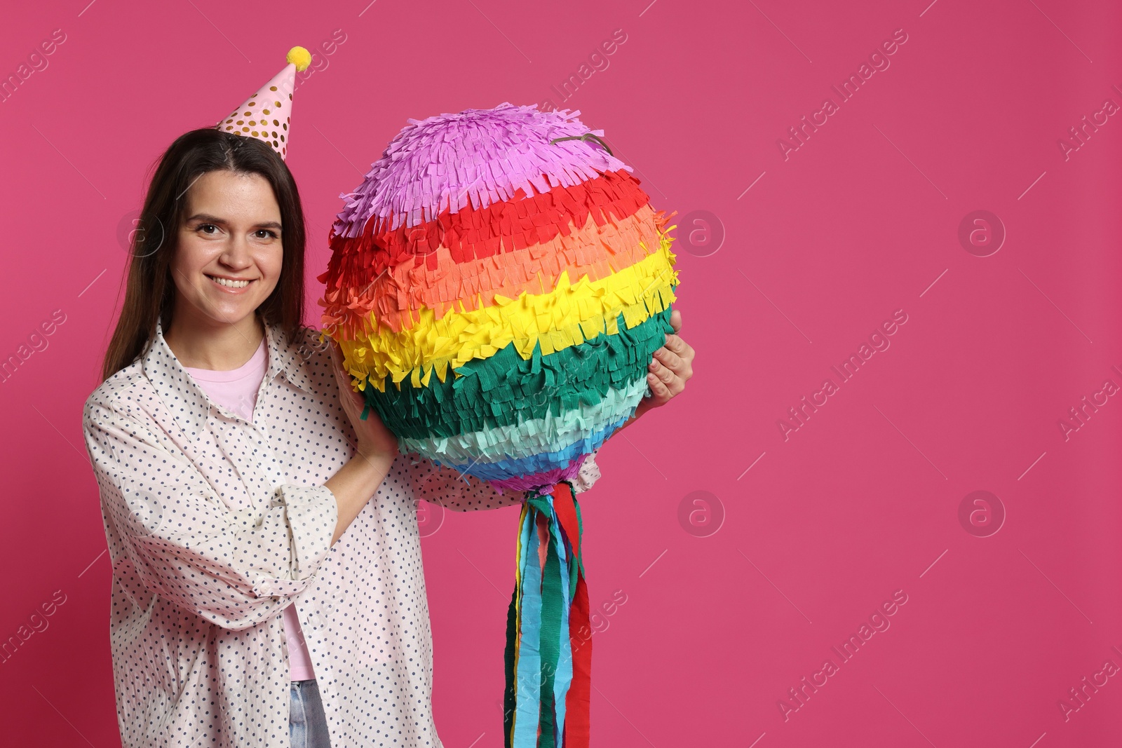 Photo of Happy woman with colorful pinata on pink background, space for text