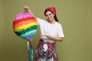 Photo of Happy woman with colorful pinata on green background, space for text