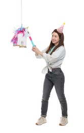 Photo of Happy woman hitting unicorn shaped pinata with stick on white background