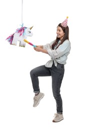 Happy woman hitting unicorn shaped pinata with stick on white background