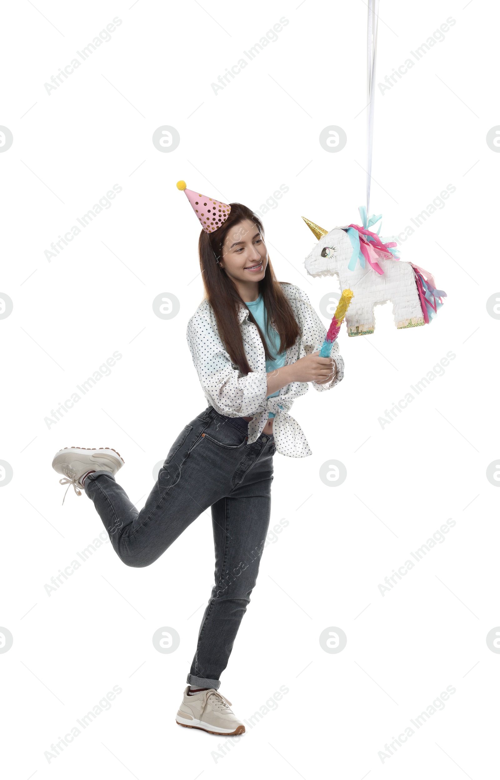 Photo of Happy woman hitting unicorn shaped pinata with stick on white background