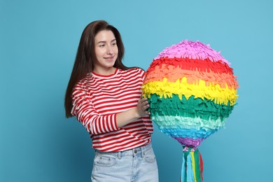 Photo of Happy woman with pinata on light blue background