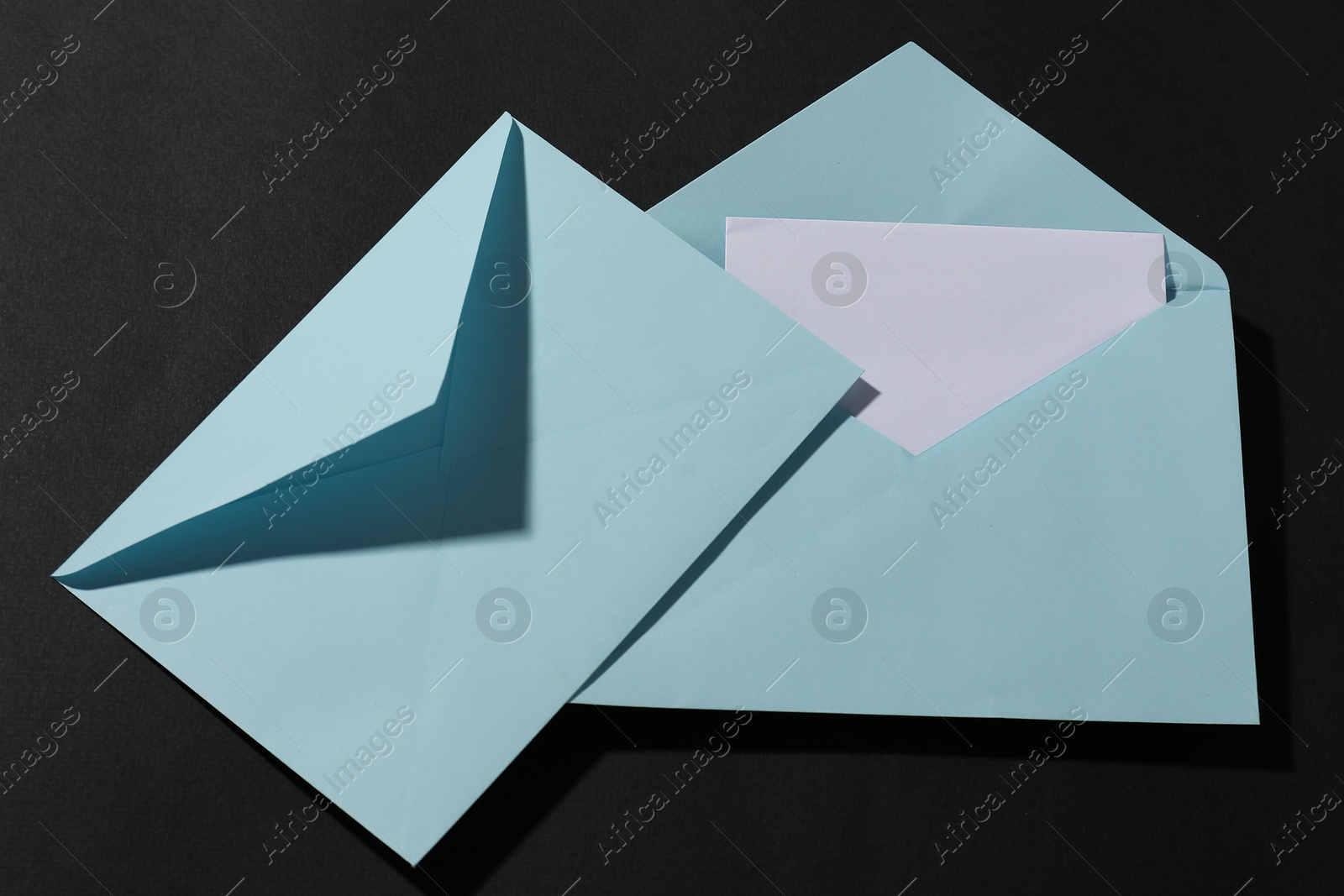 Photo of Paper envelopes with letter on black background, top view. Mockup for design