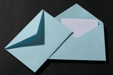 Photo of Paper envelopes with letter on black background, top view. Mockup for design