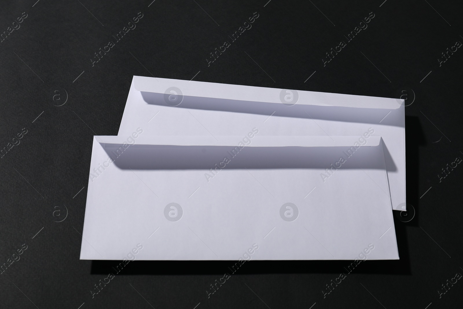 Photo of Paper envelopes on black background, above view. Mockup for design